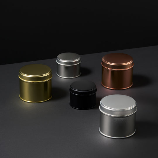 Collection of welded side seam tins in black, rose gold, silver, and gold