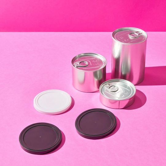 Pressitins on pink background with two black lids and one white. 